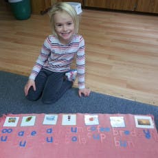 Child kneeling on a rug with letter and picture cards