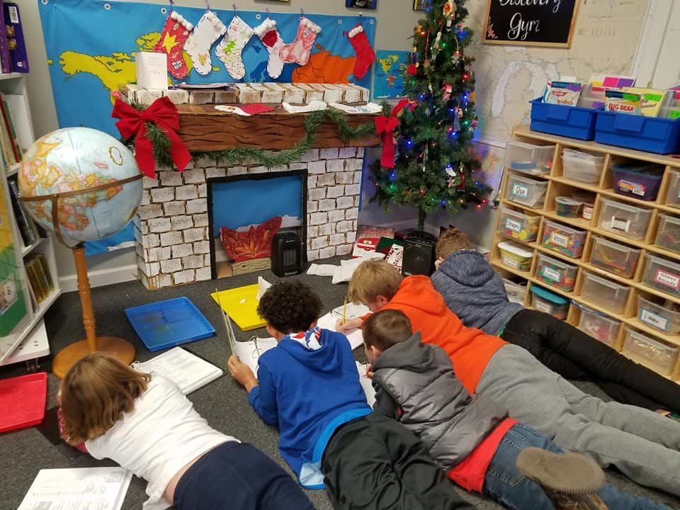 Children lying on the floor writing in a classroom