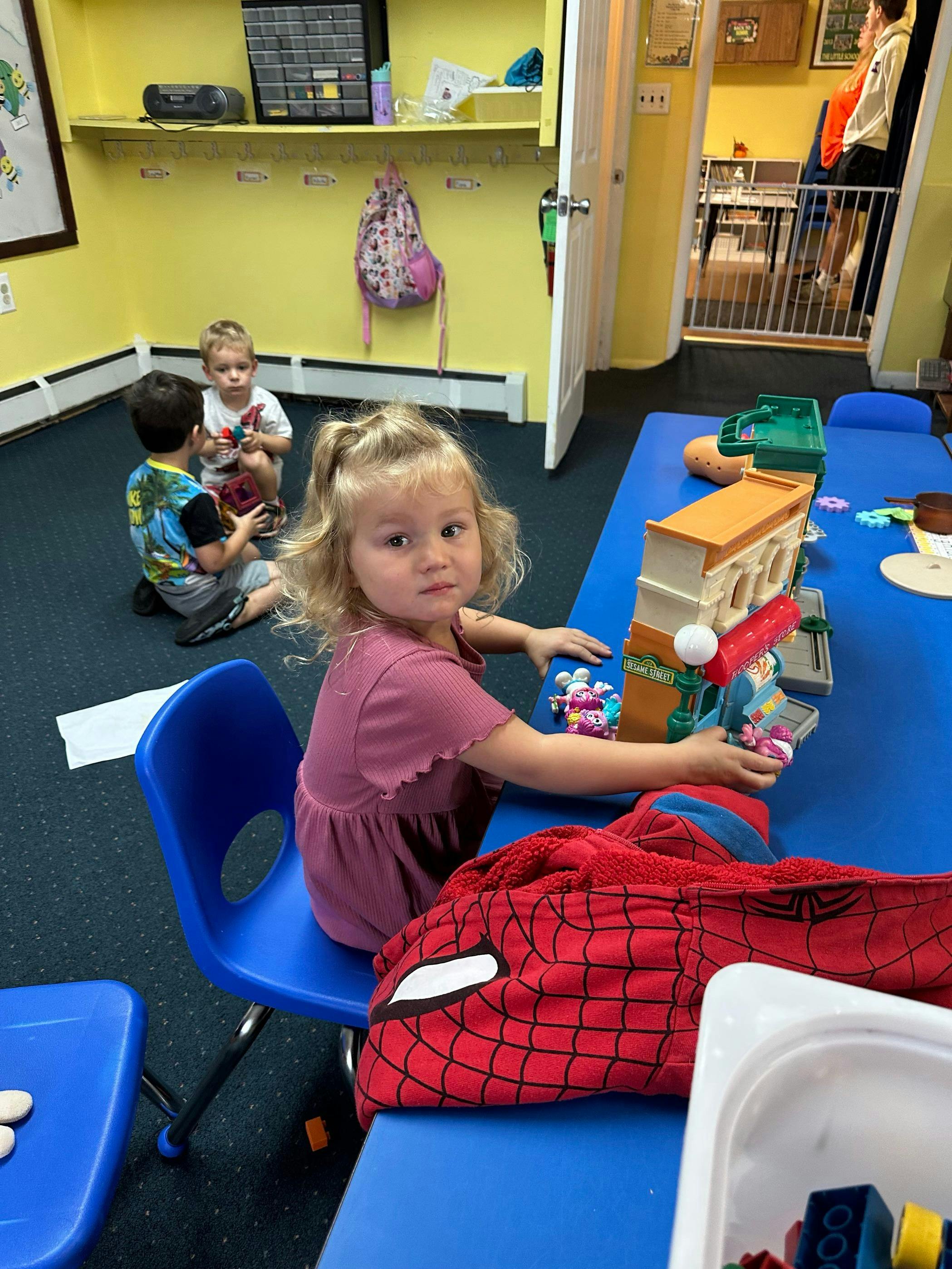 Child playing with a toy building at a blue table