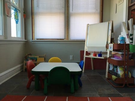 Children's table and chairs in a room with an easel and windows