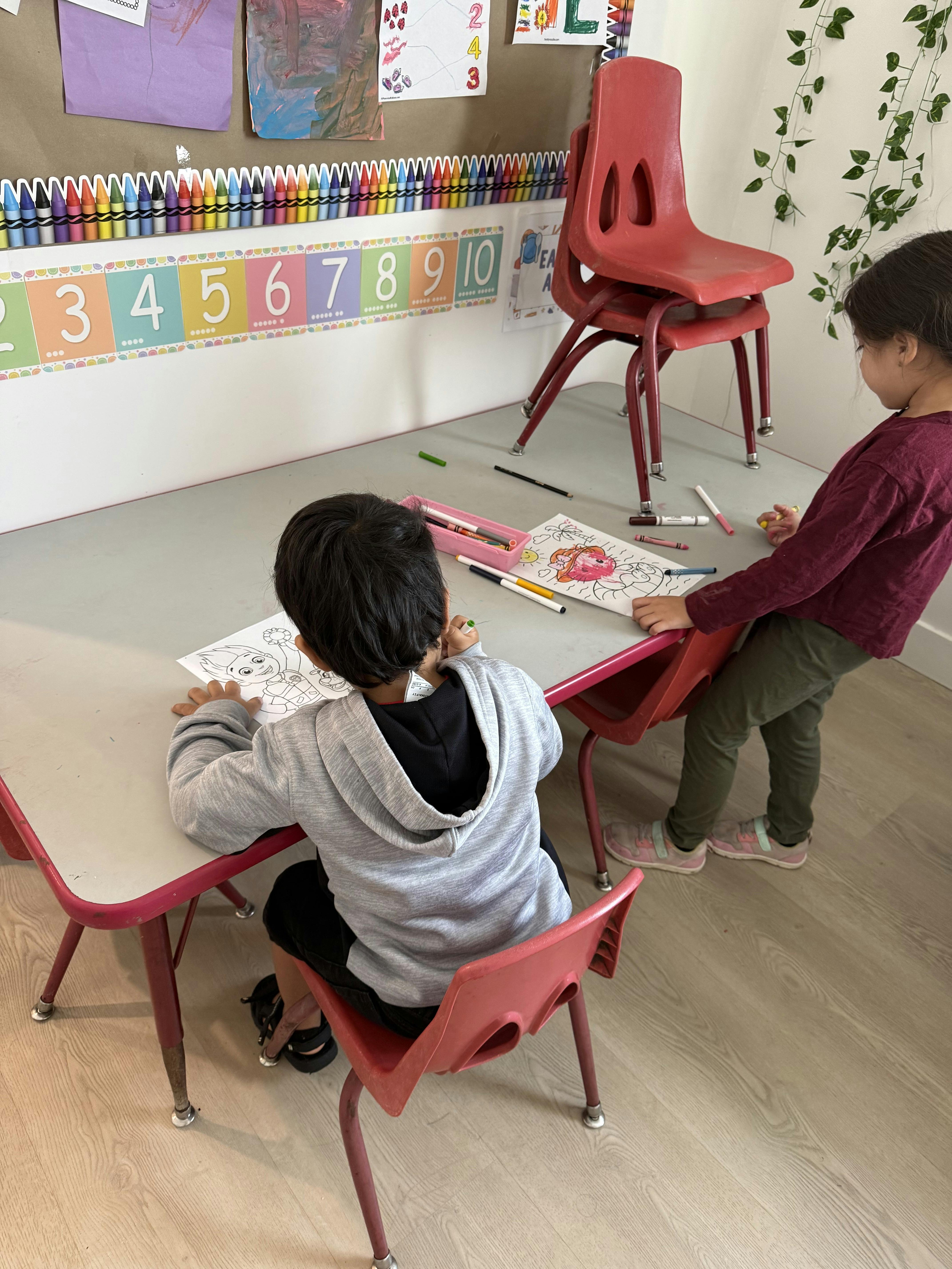 Two children coloring at a classroom table