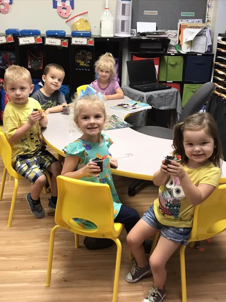 Children sitting at a table holding small cups