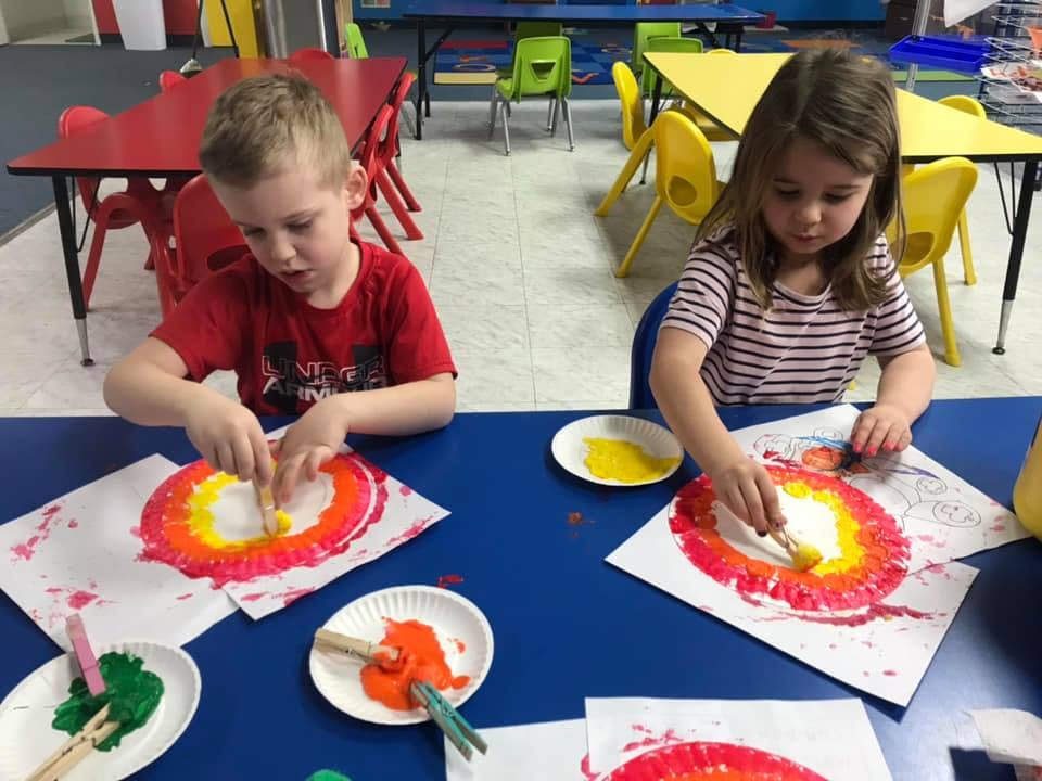 Two children painting at a table in a classroom