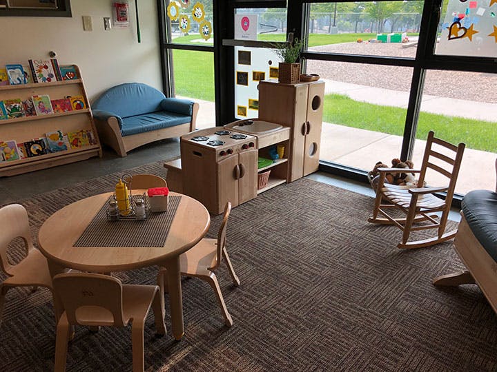 Children's play area with small table and chairs, toy kitchen, and bookshelf