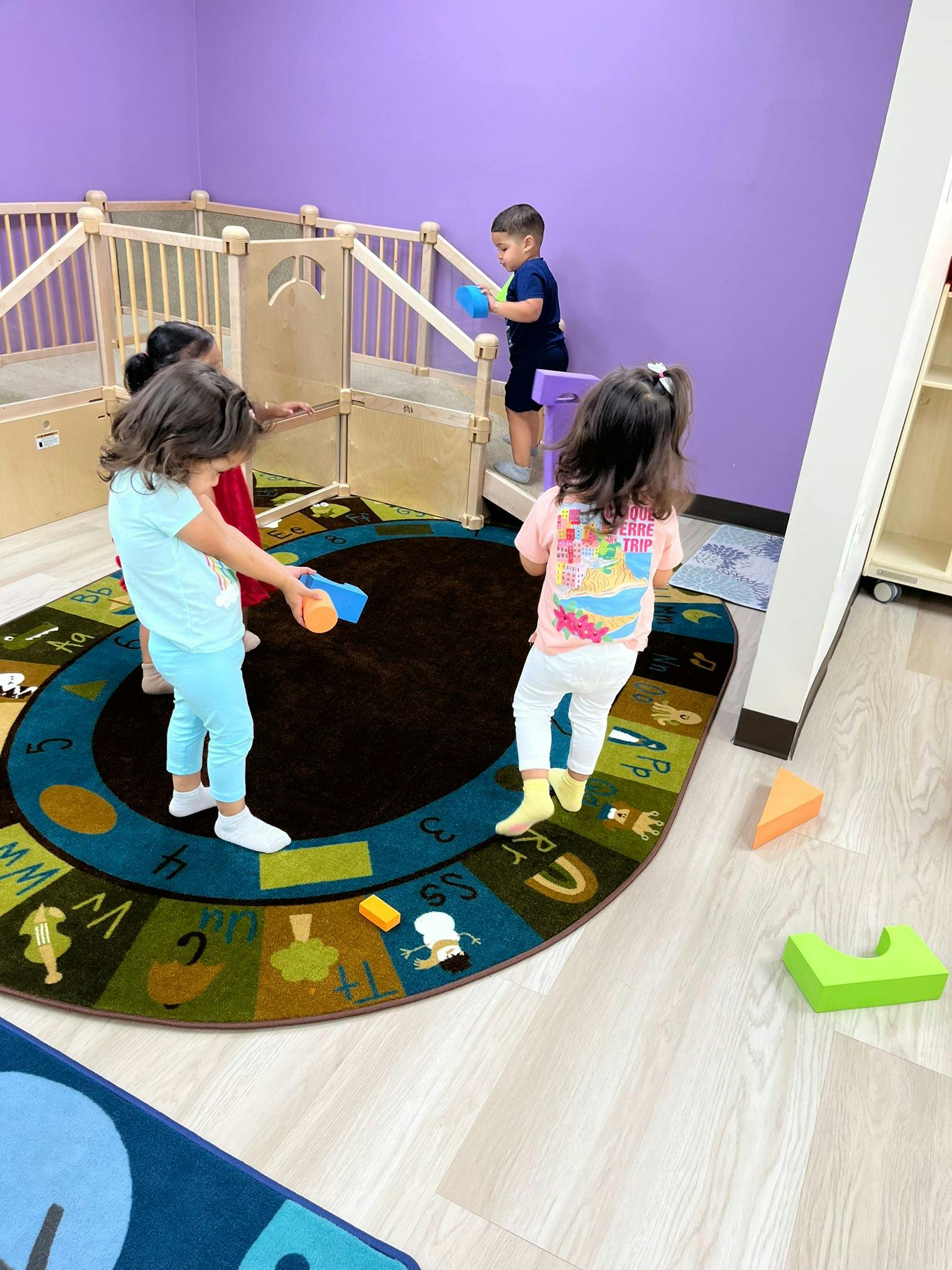 Children playing with blocks on a colorful rug in a classroom