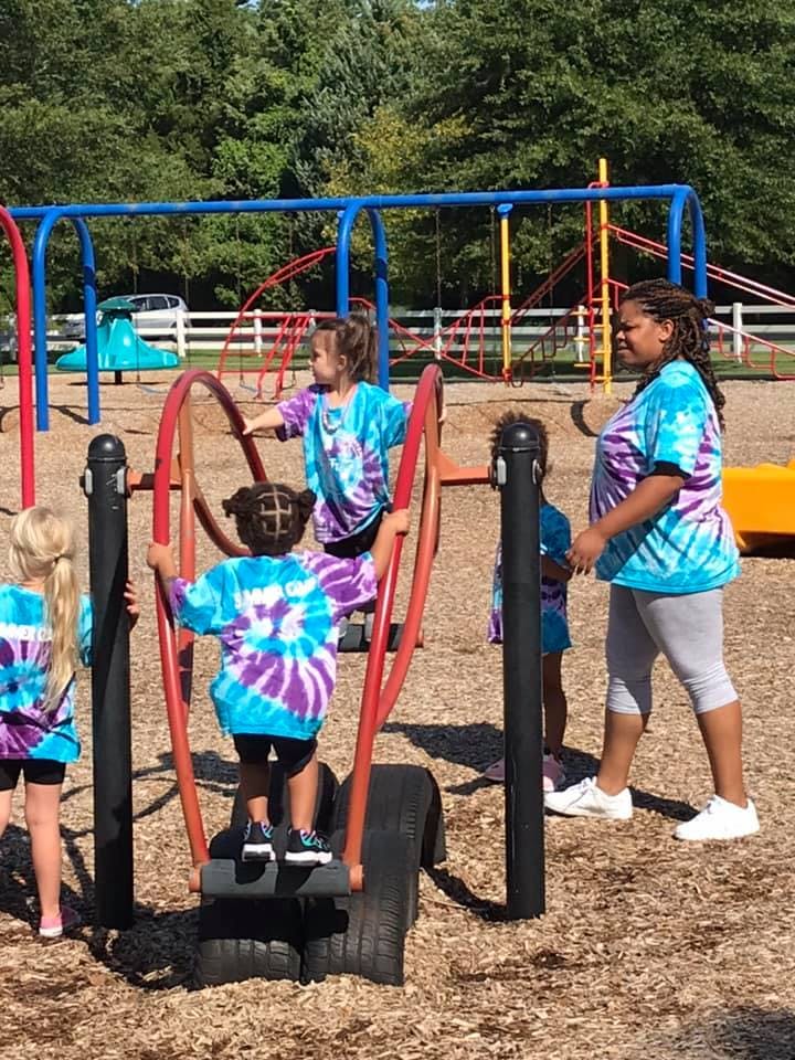 Children playing on playground equipment with an adult nearby