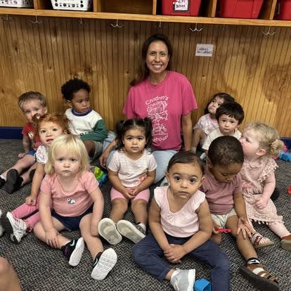 Adult and group of children sitting on the floor in a classroom