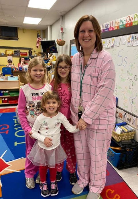Adult and three children in pajamas in a classroom