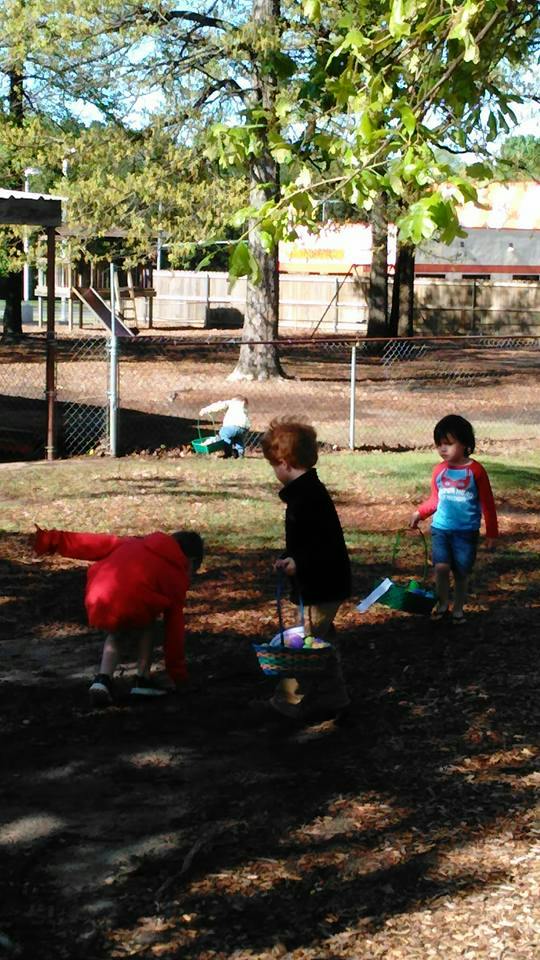Three children with baskets on a grassy area