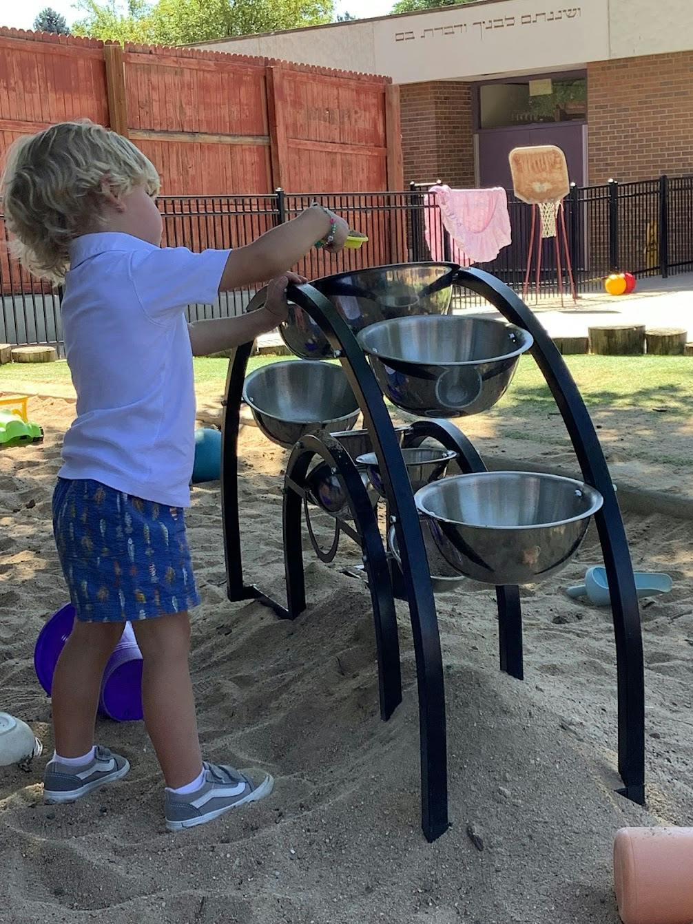 Child playing with a metal water and sand sensory station