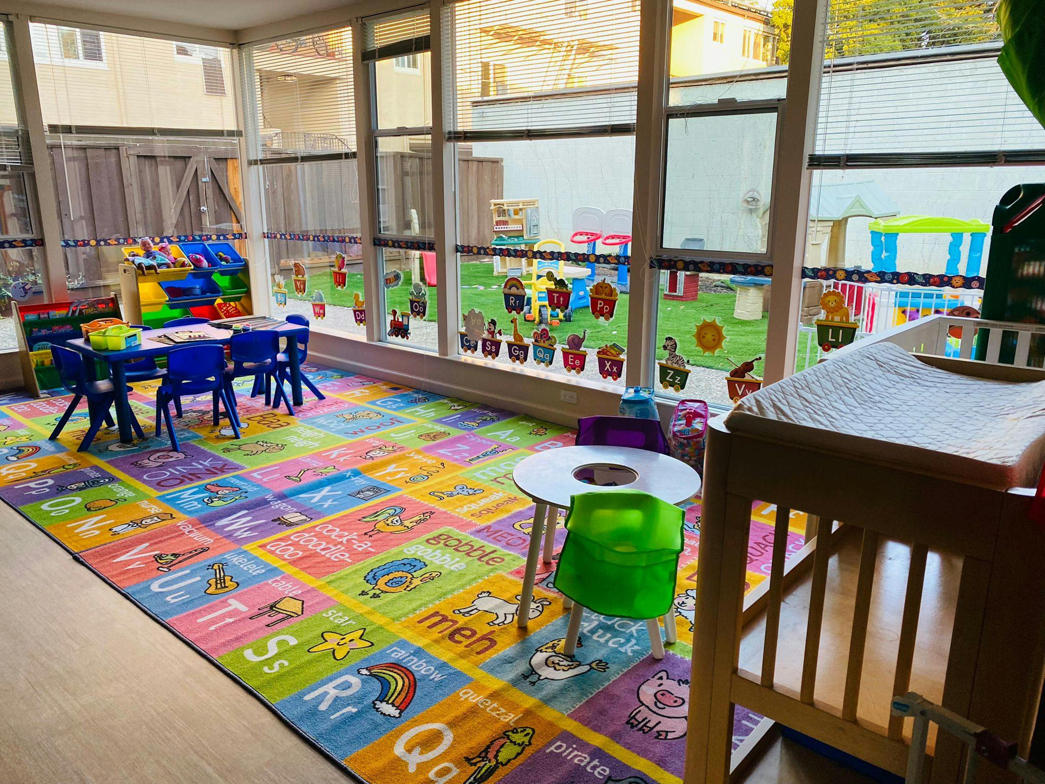 Child's play area with alphabet rug, small tables, and crib