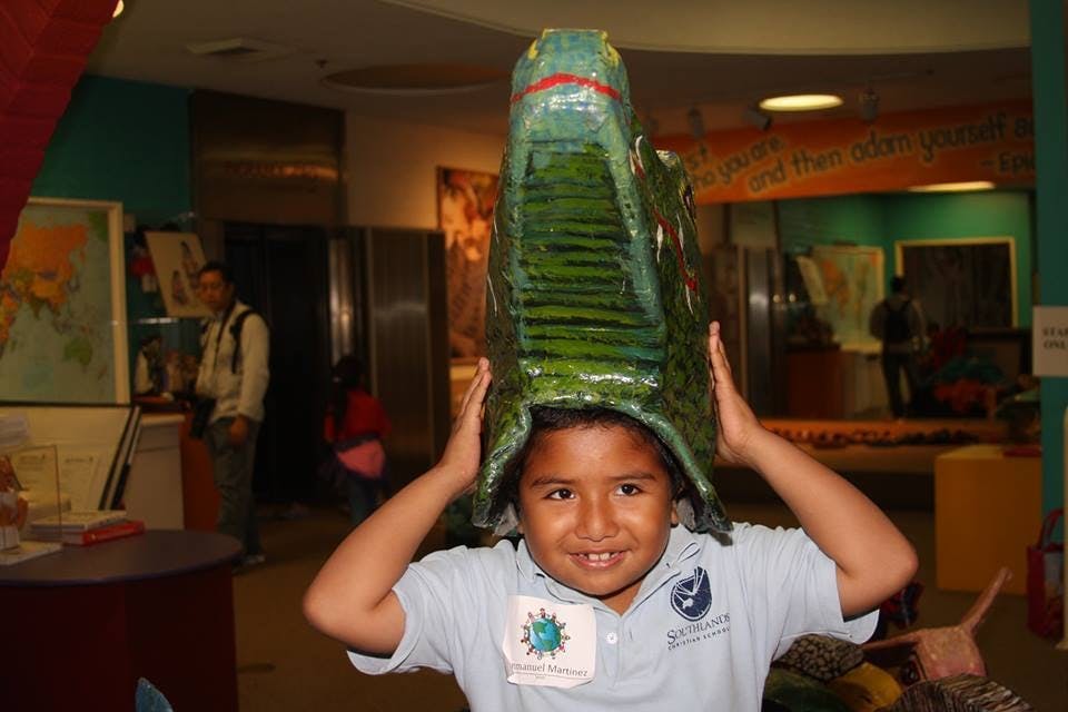 Child wearing a large green dinosaur head costume