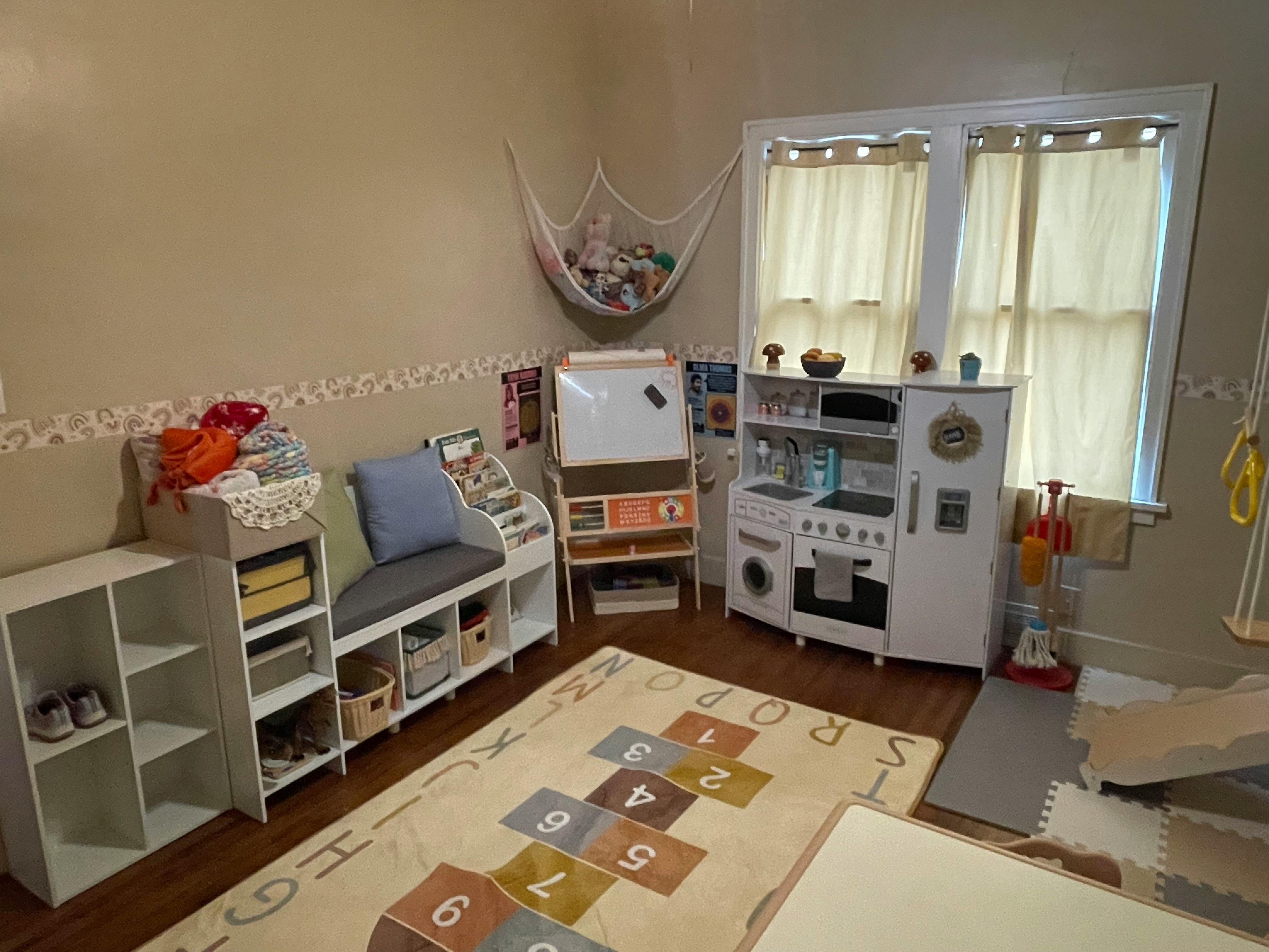 Playroom with a hopscotch rug, toy kitchen, and storage shelves