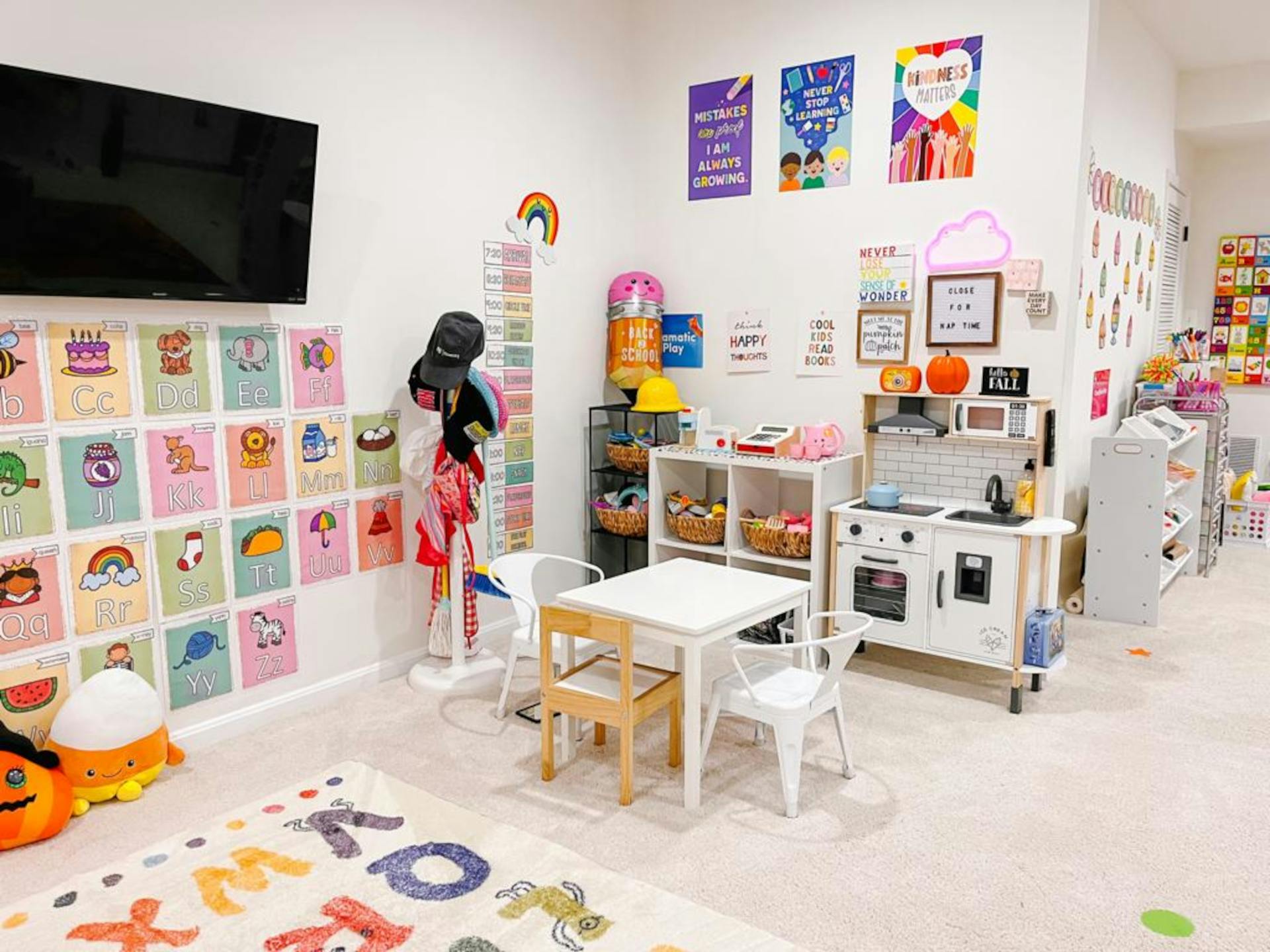 Children's play area with a small table and chairs, play kitchen, and colorful wall decorations