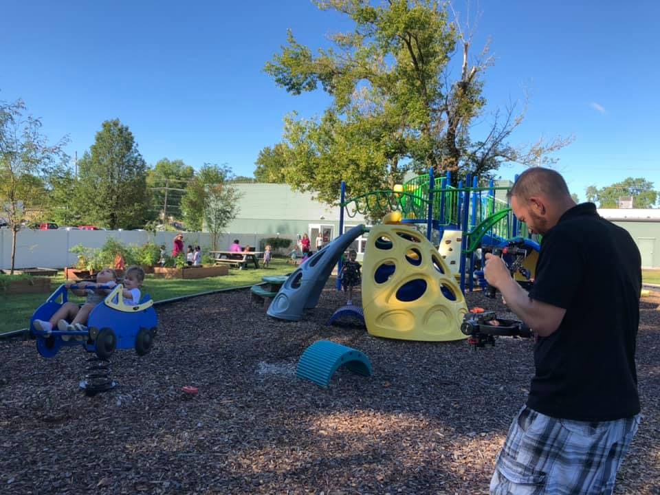Person filming on a playground with children playing