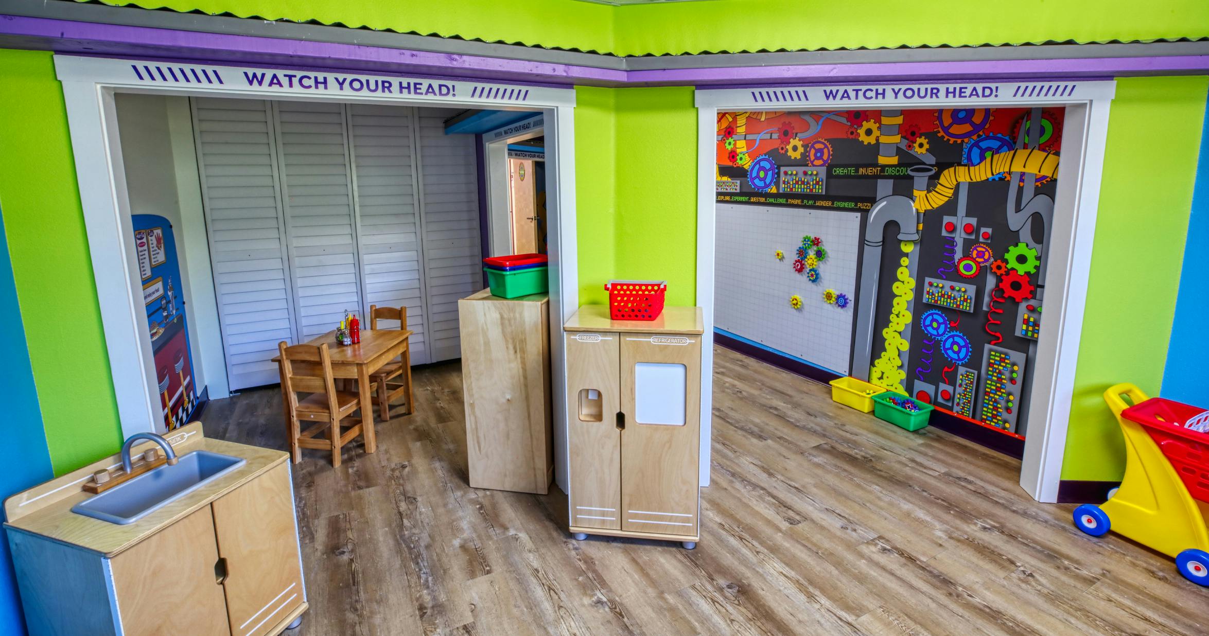 Playroom with colorful walls and child-sized furniture, text "WATCH YOUR HEAD!"