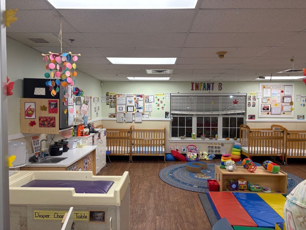 An infant daycare classroom with cribs, changing table, and play area