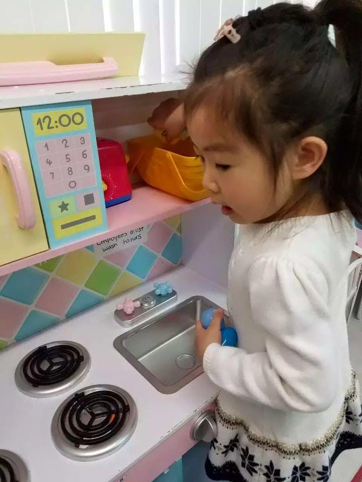 Child playing with a toy kitchen set