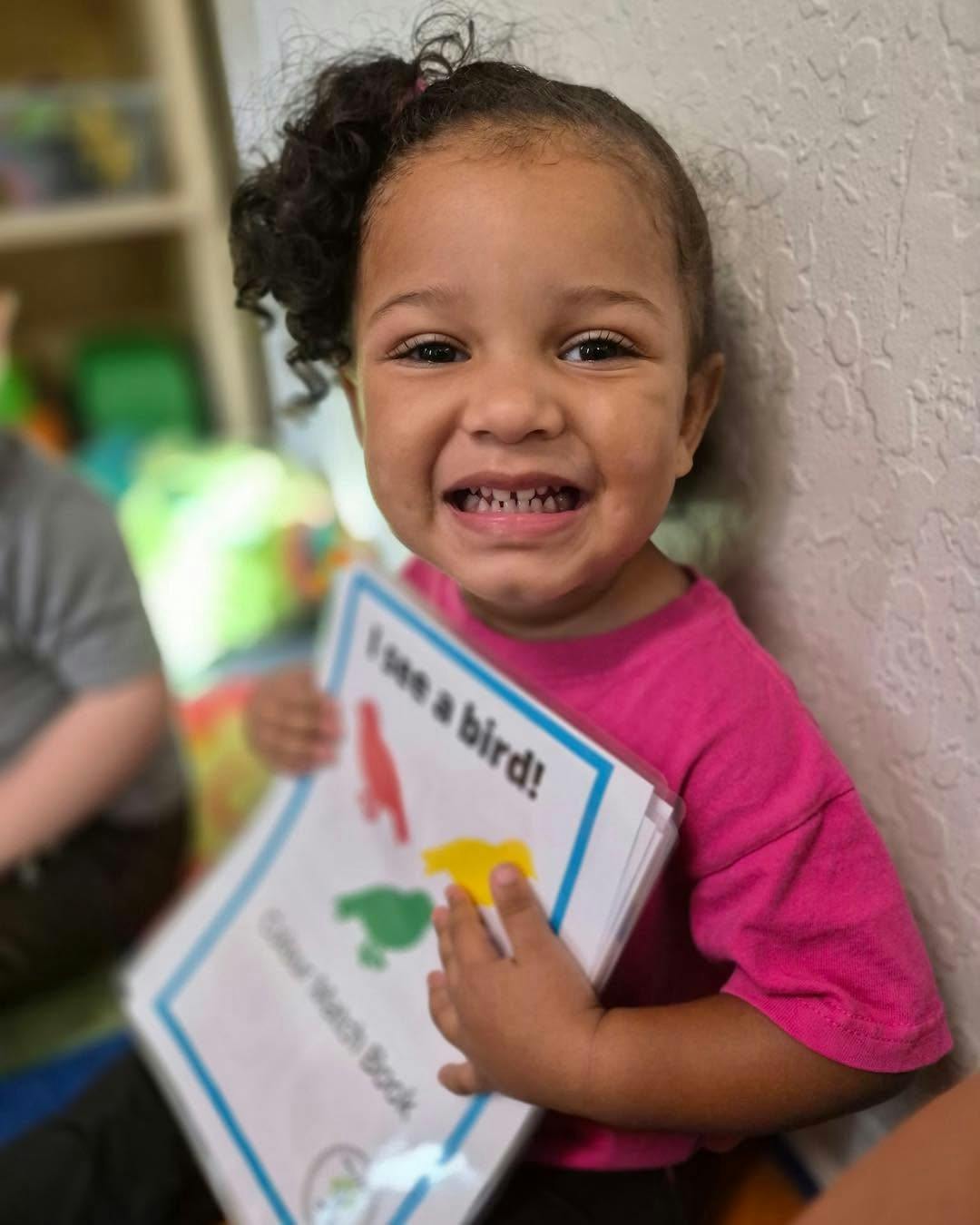 Child holding a book titled I see a bird