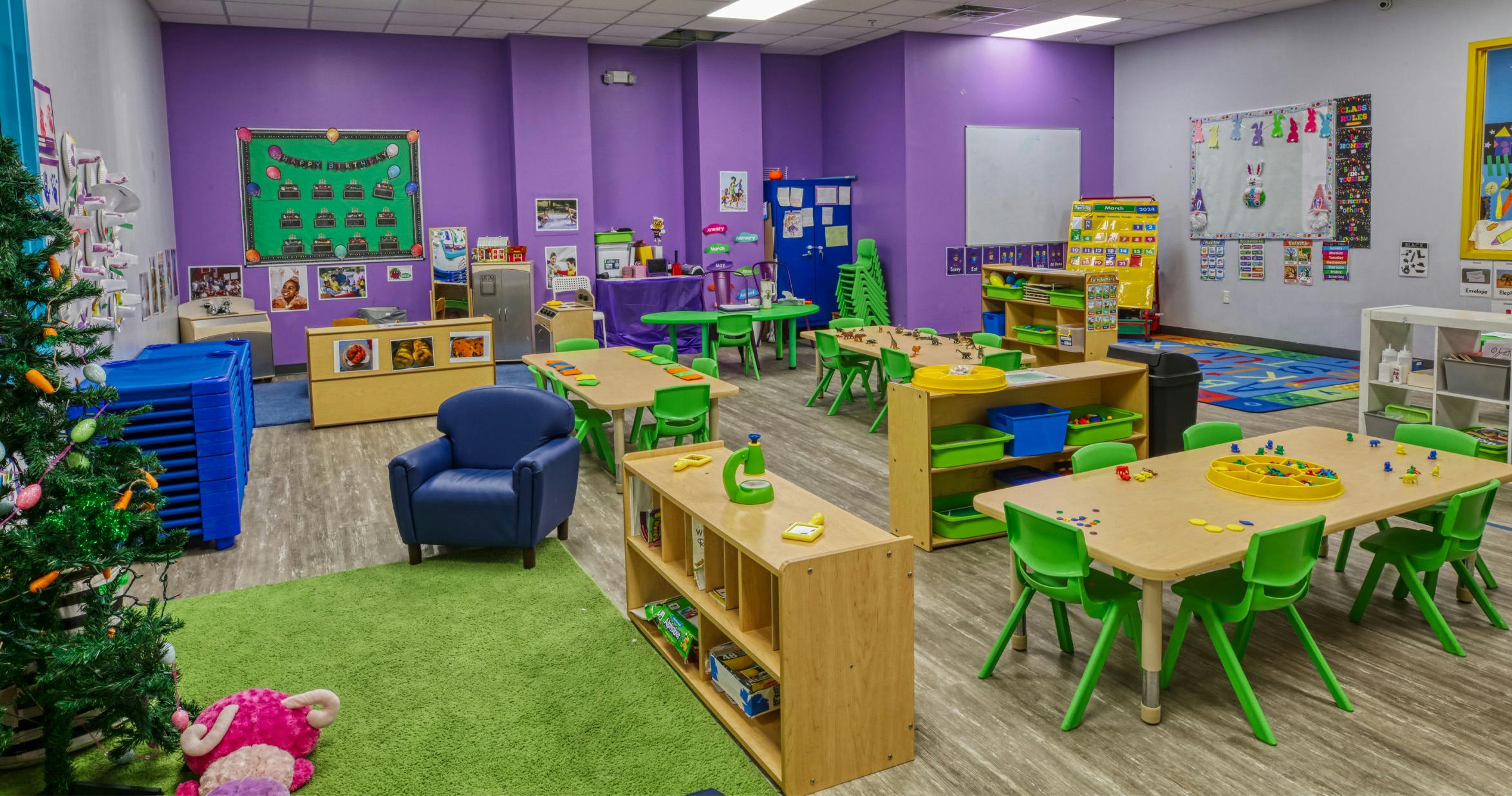 Colorful classroom with small tables and chairs, toys, and decorations on purple walls