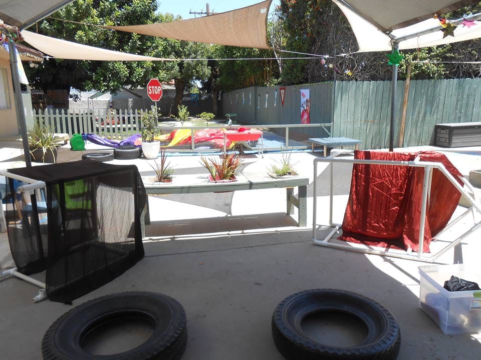 Outdoor play area with shade sails, benches, and play equipment