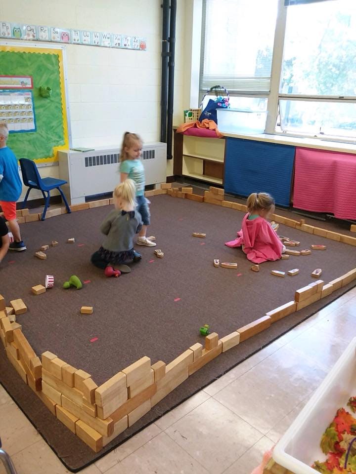 Children playing with wooden blocks in a classroom