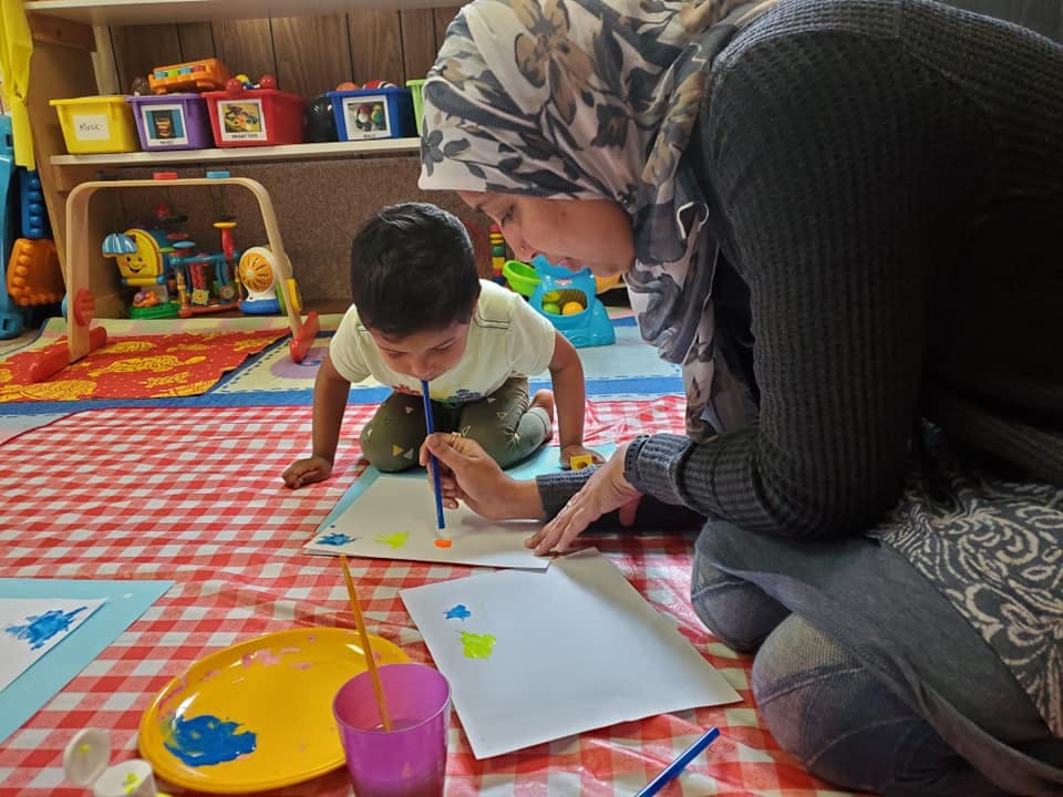 Person and child painting on paper
