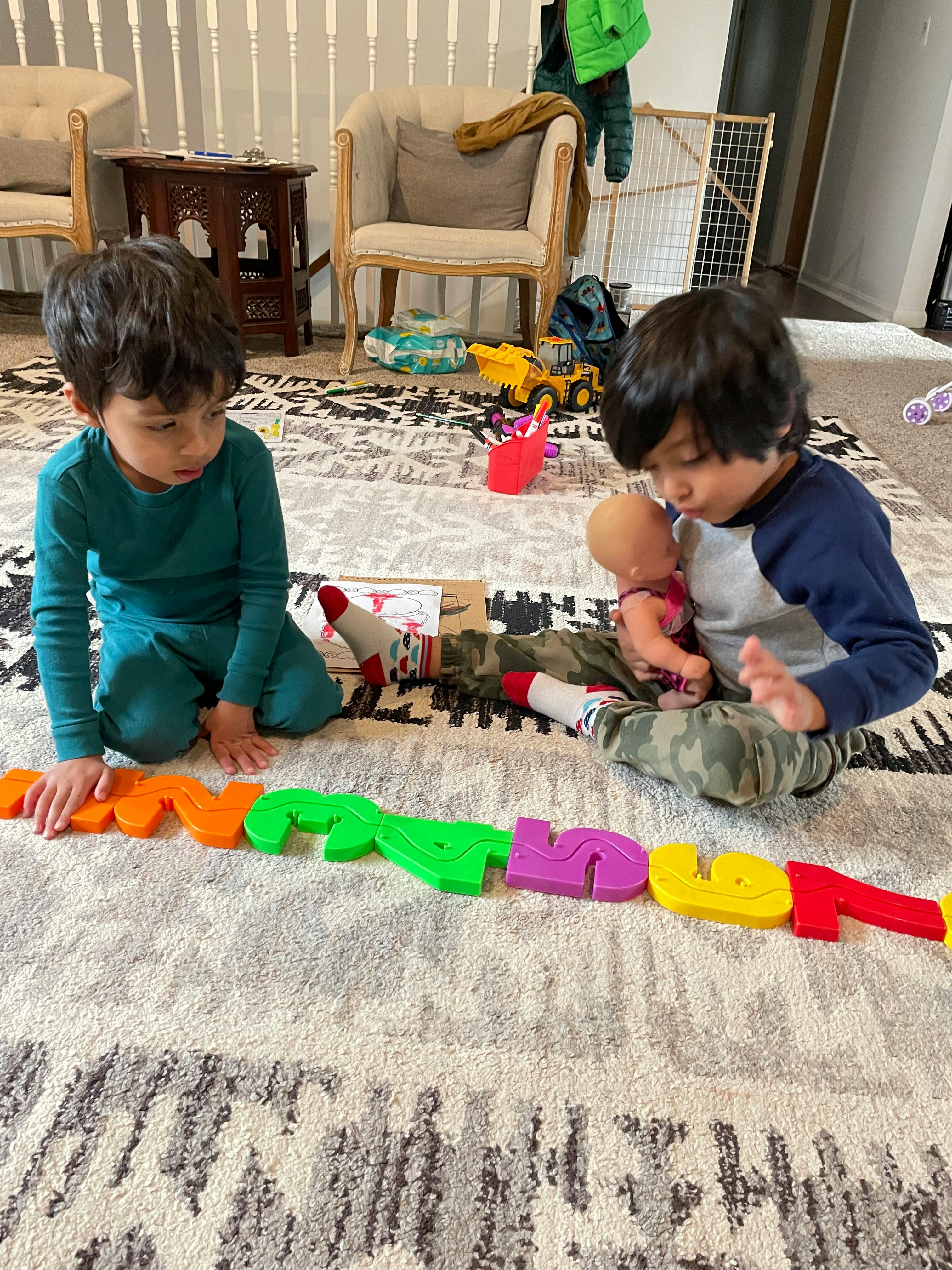 Two children playing on a rug with colorful letter toys
