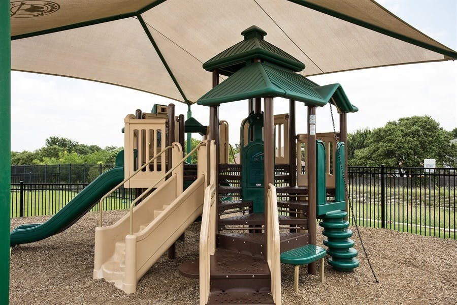 Playground with slides, stairs, and climbing structures under a shade canopy
