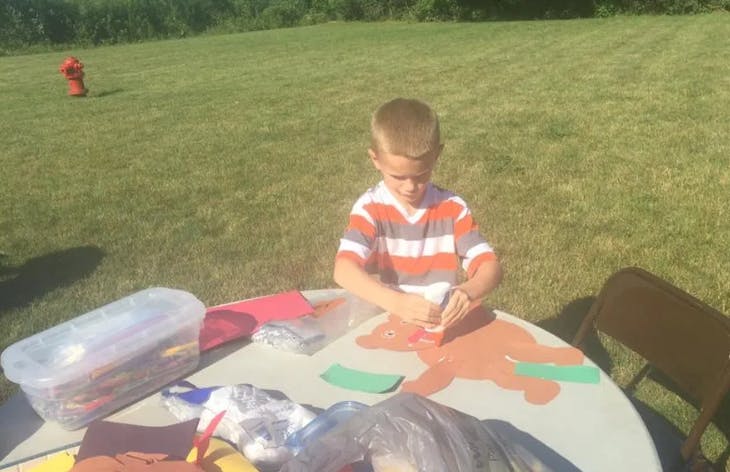 Child doing crafts at a table outdoors