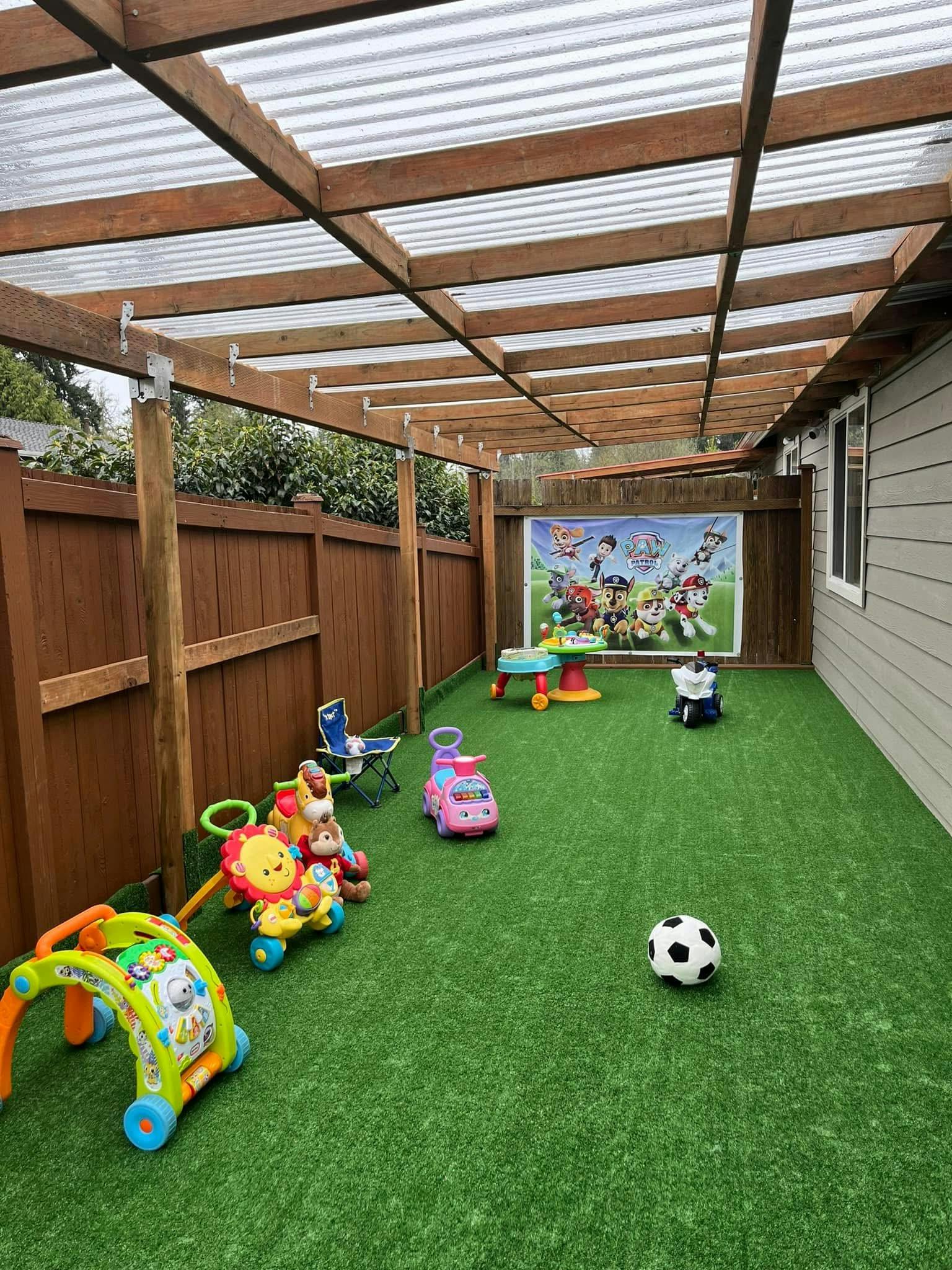 Covered backyard patio with artificial turf and various toys