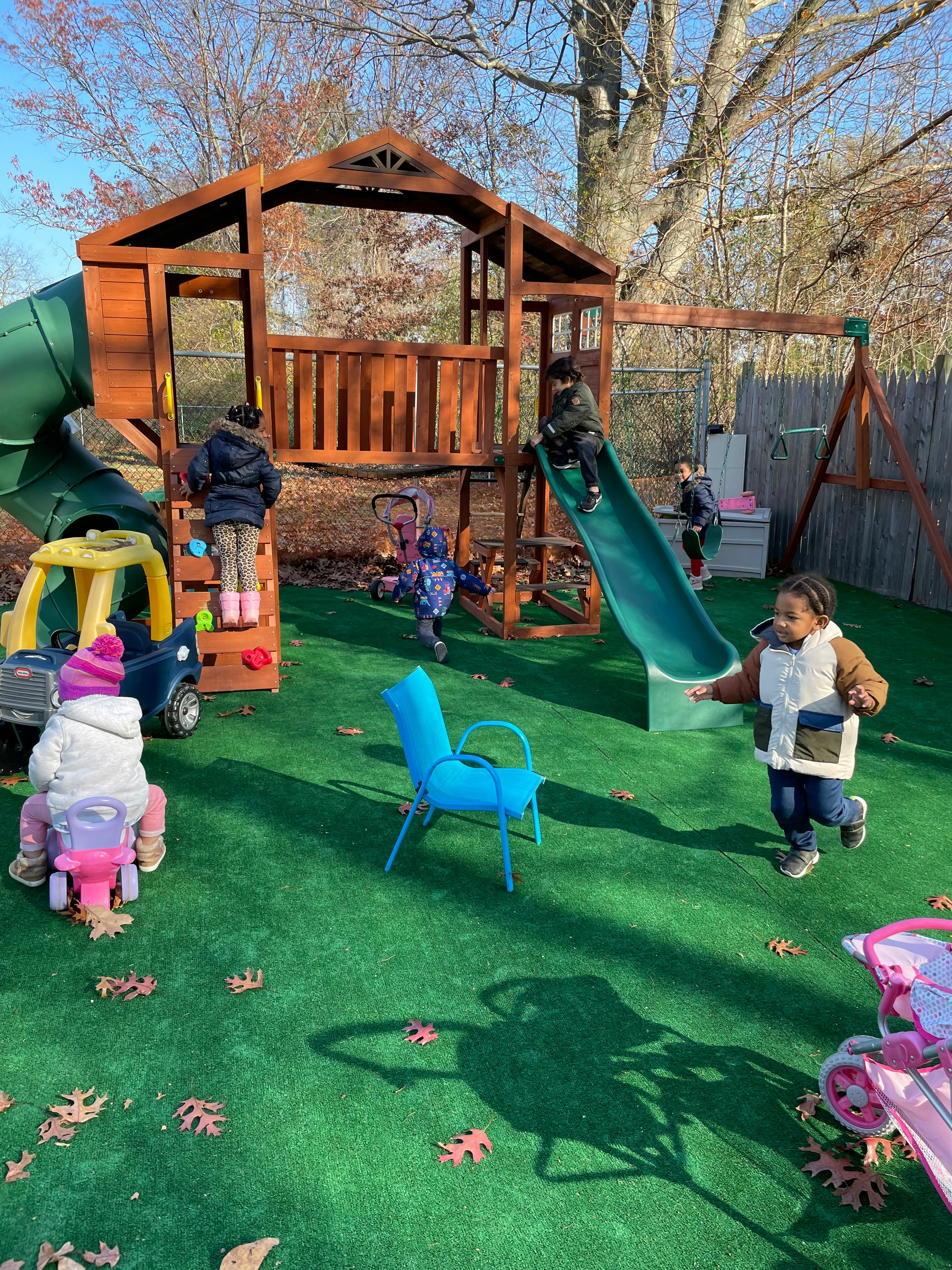 Children playing on a wooden playground structure with slides and swings