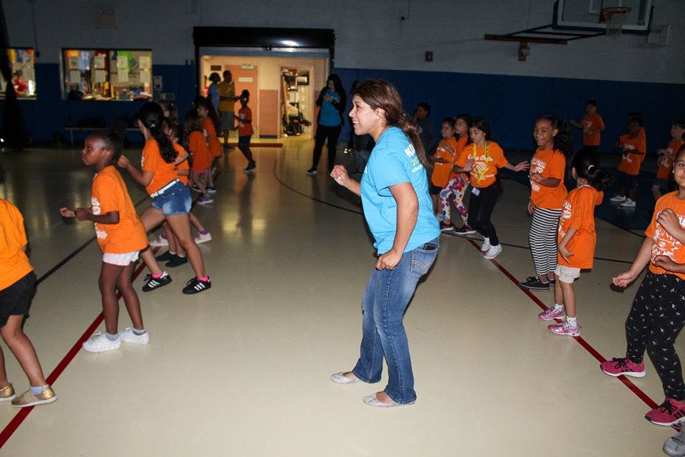 Person leading a group of children in an activity in a gymnasium