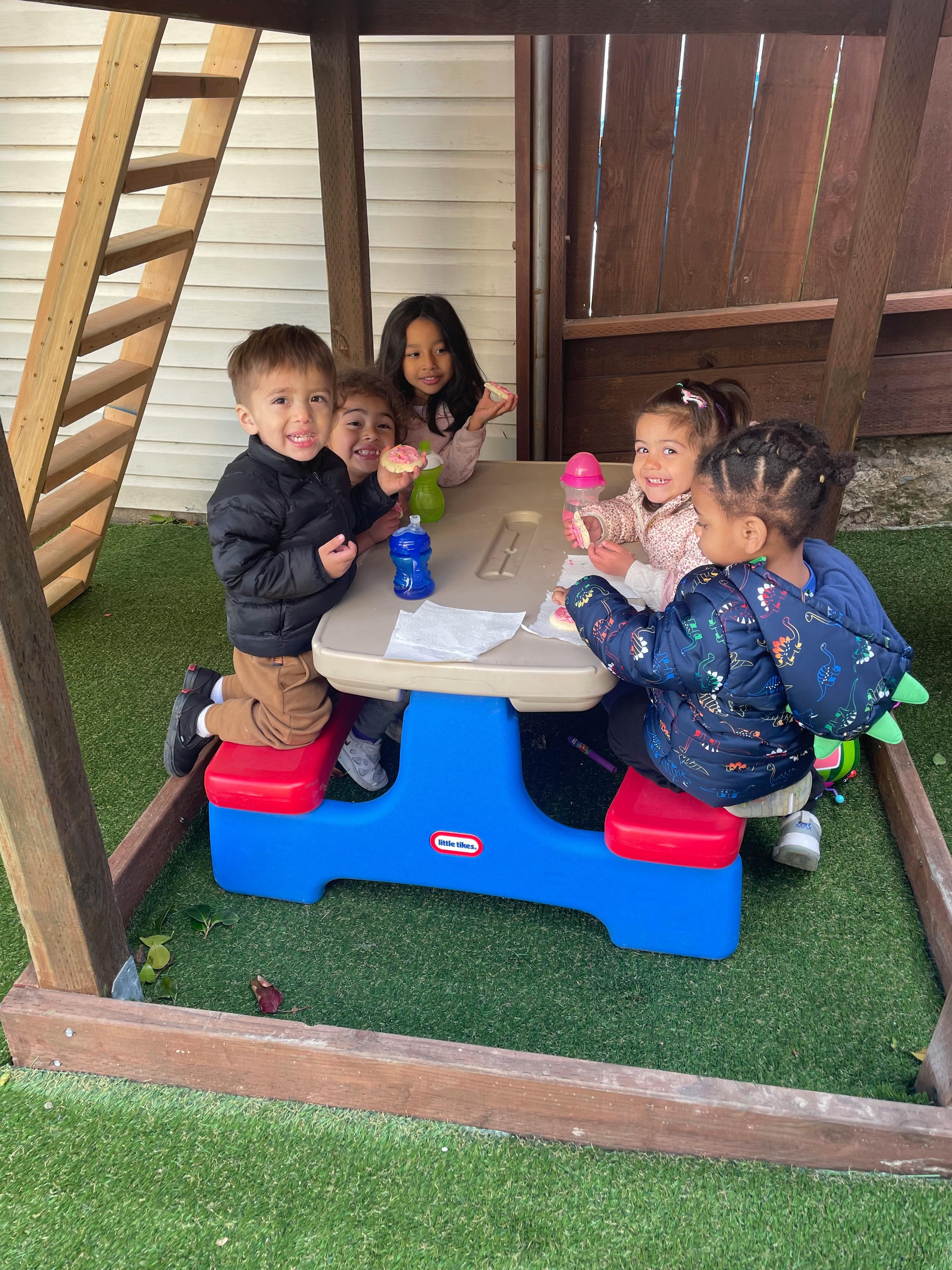 Children sitting at a small table outdoors