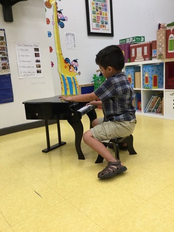 Child playing a toy piano in a classroom