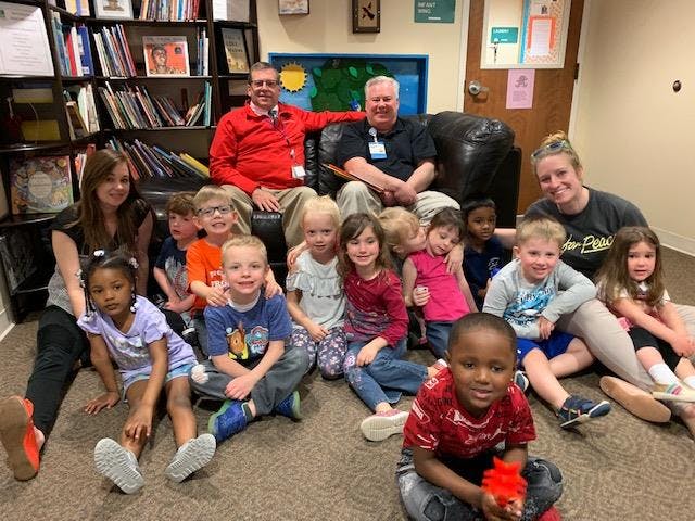 Adults and children sitting on the floor and a couch