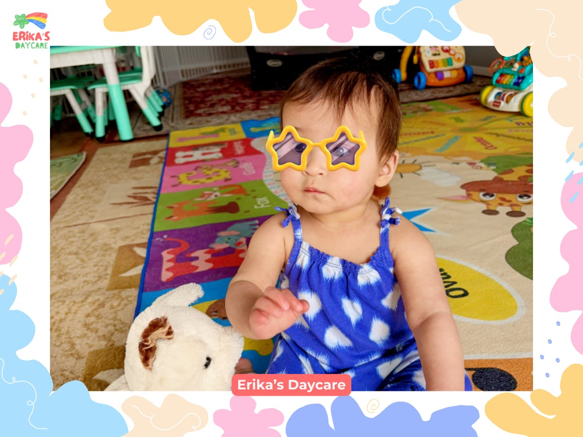 Child wearing star-shaped sunglasses sitting on a play mat