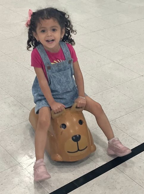 Child riding a brown bear-shaped bouncy toy