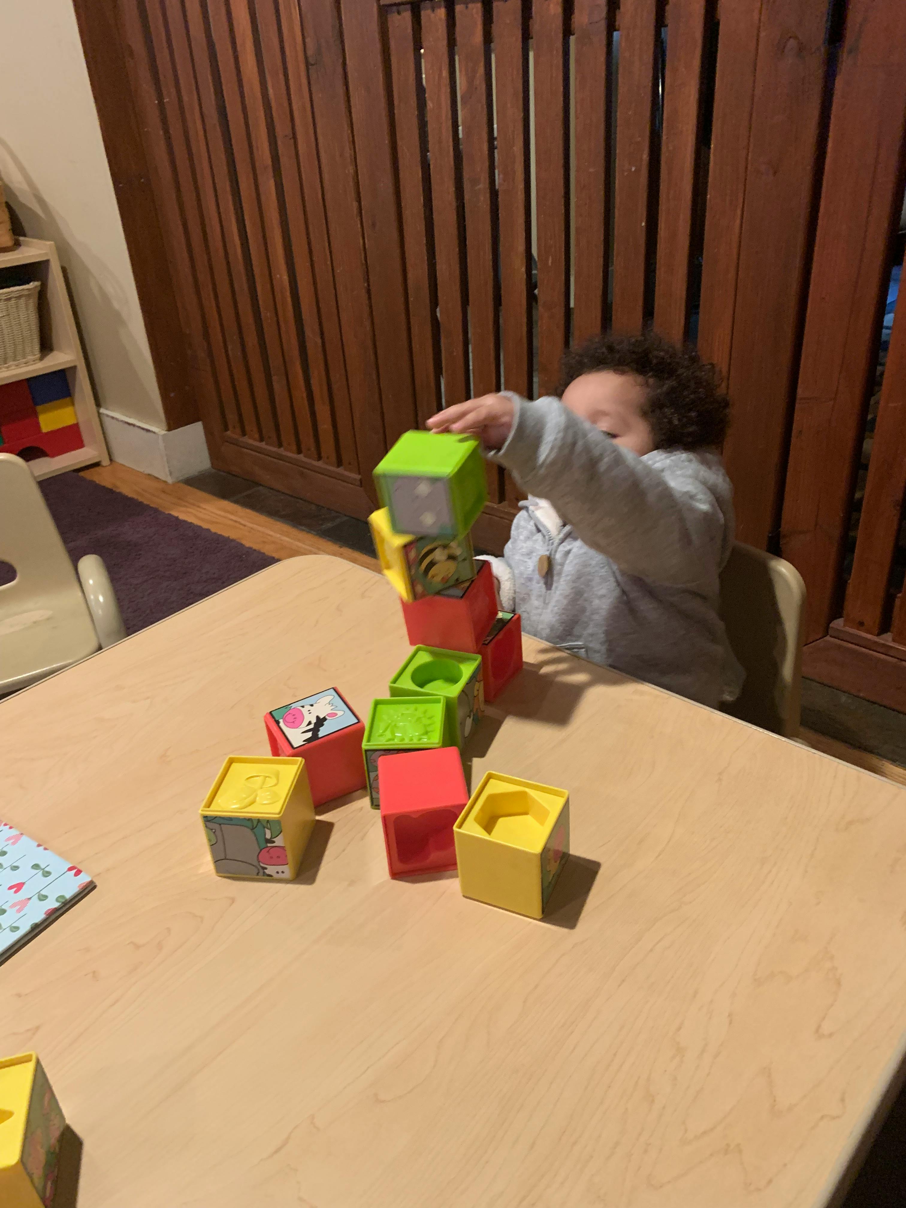 Child stacking colorful blocks on a table