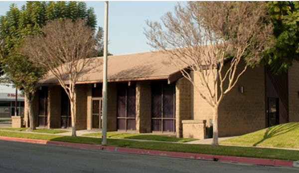 Building with brown roof and dark windows, trees in front