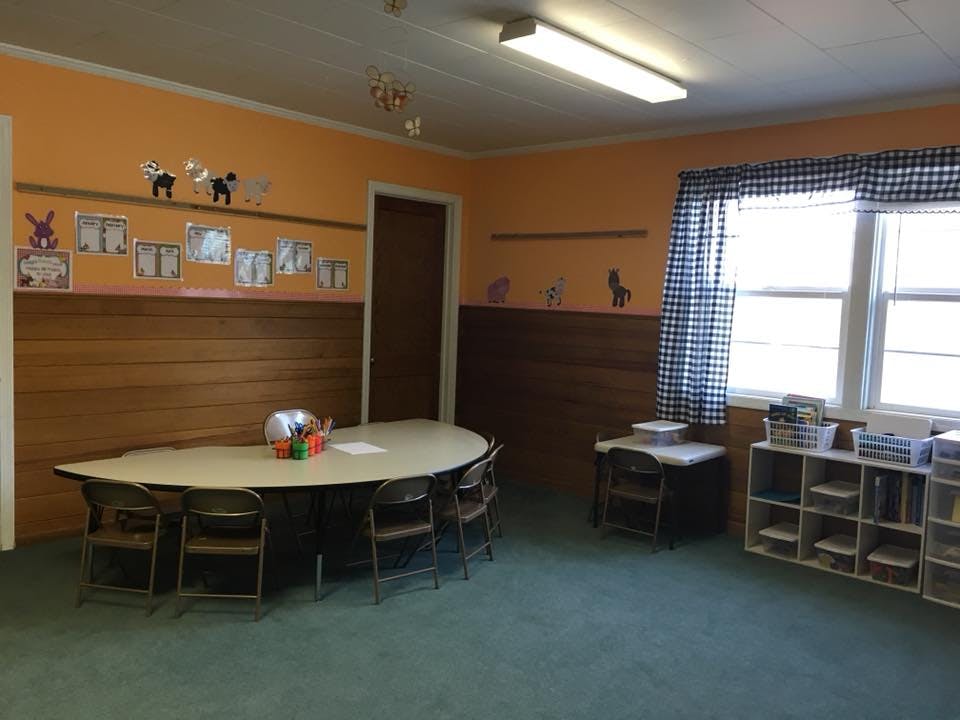 Classroom with a large table and chairs, window, and storage shelves