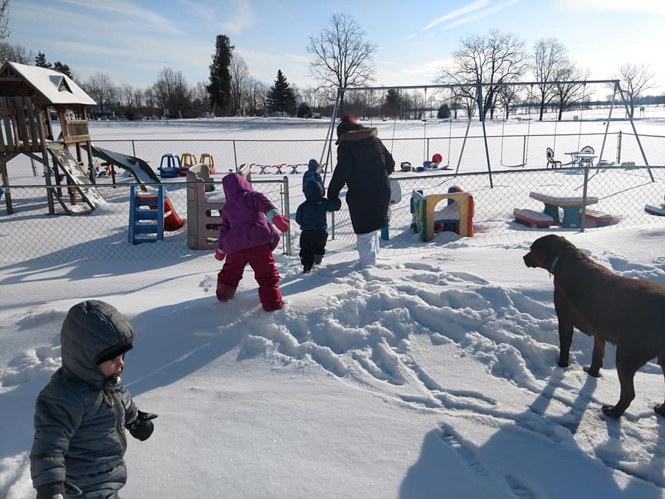 People and a dog in a snowy playground