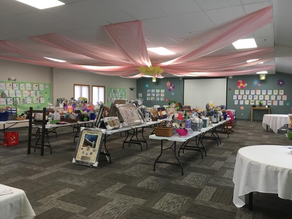 Room with tables displaying various items, pink fabric draped on ceiling