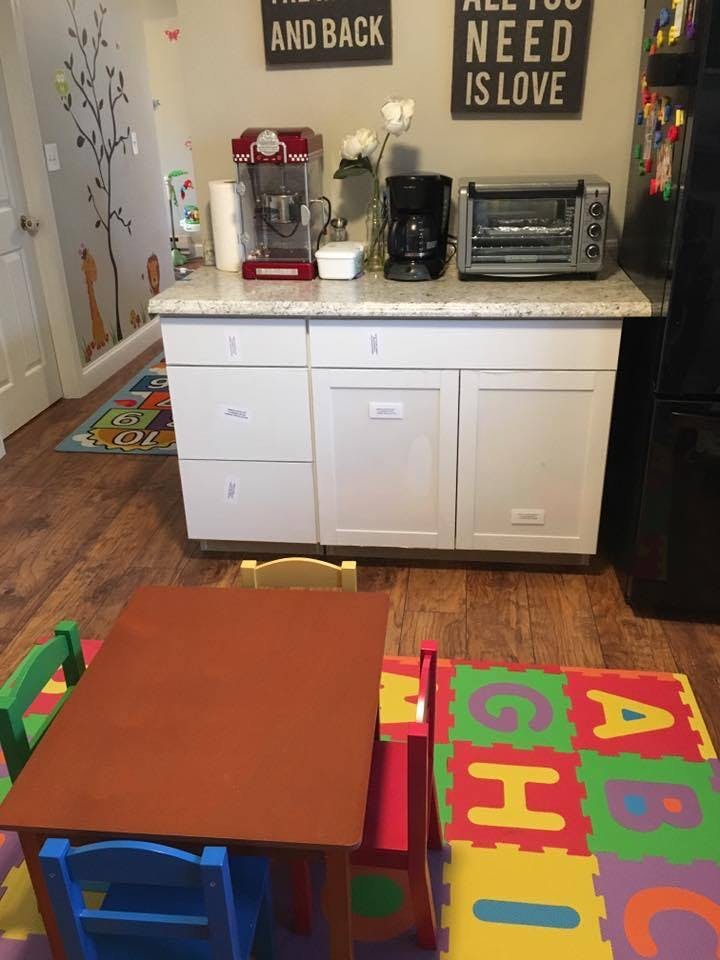 Kitchen counter with appliances, child-sized table and chairs, and alphabet mat