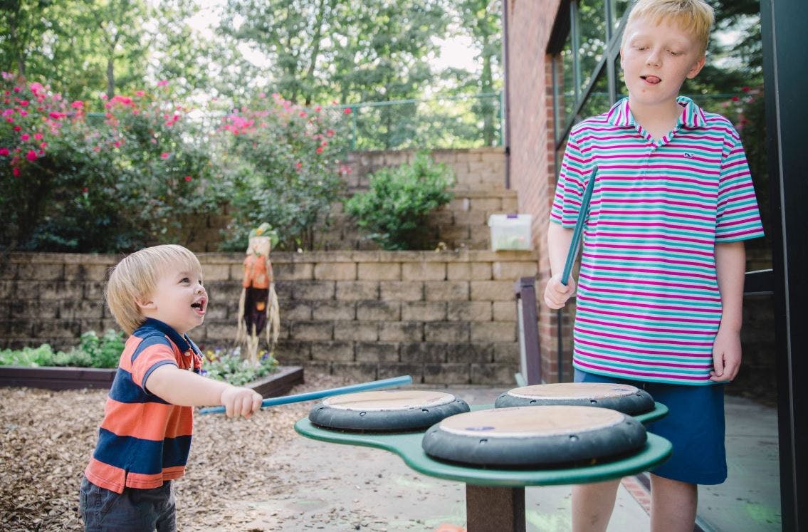 Two children playing outdoor drums