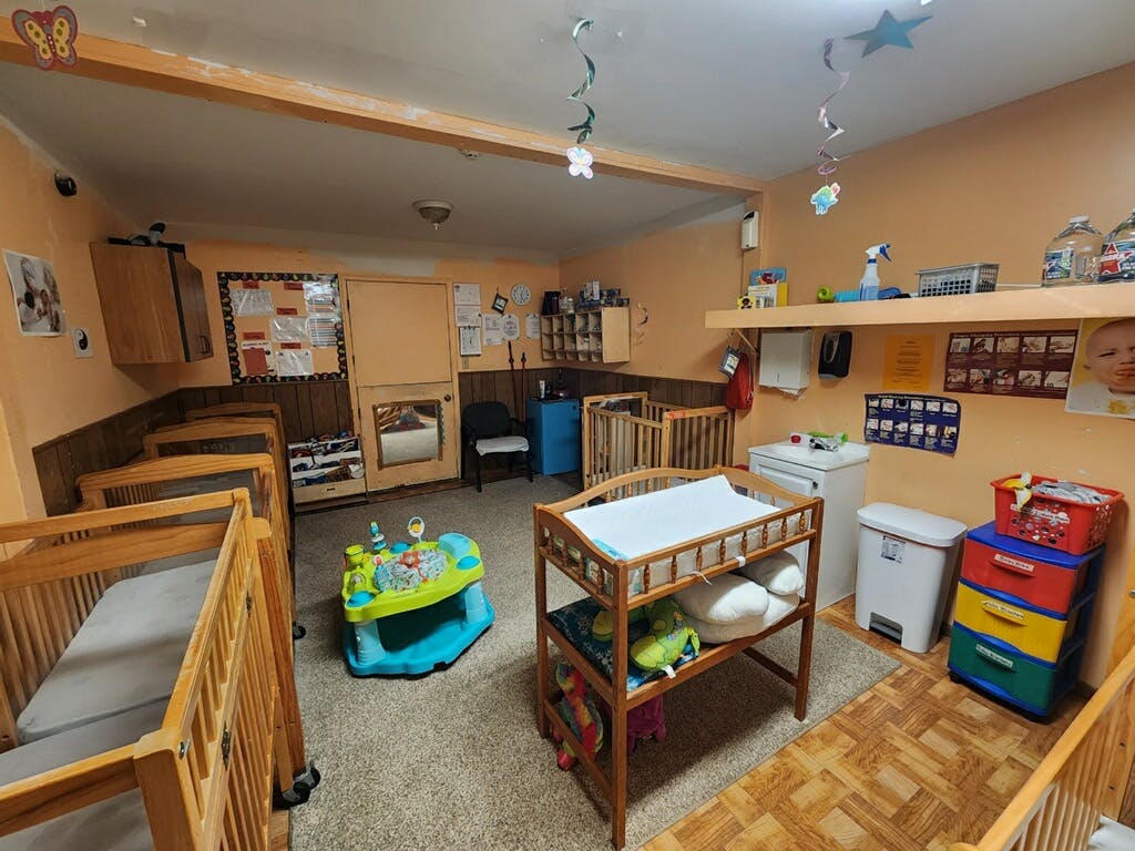 Room with multiple cribs, a changing table, and a baby activity center