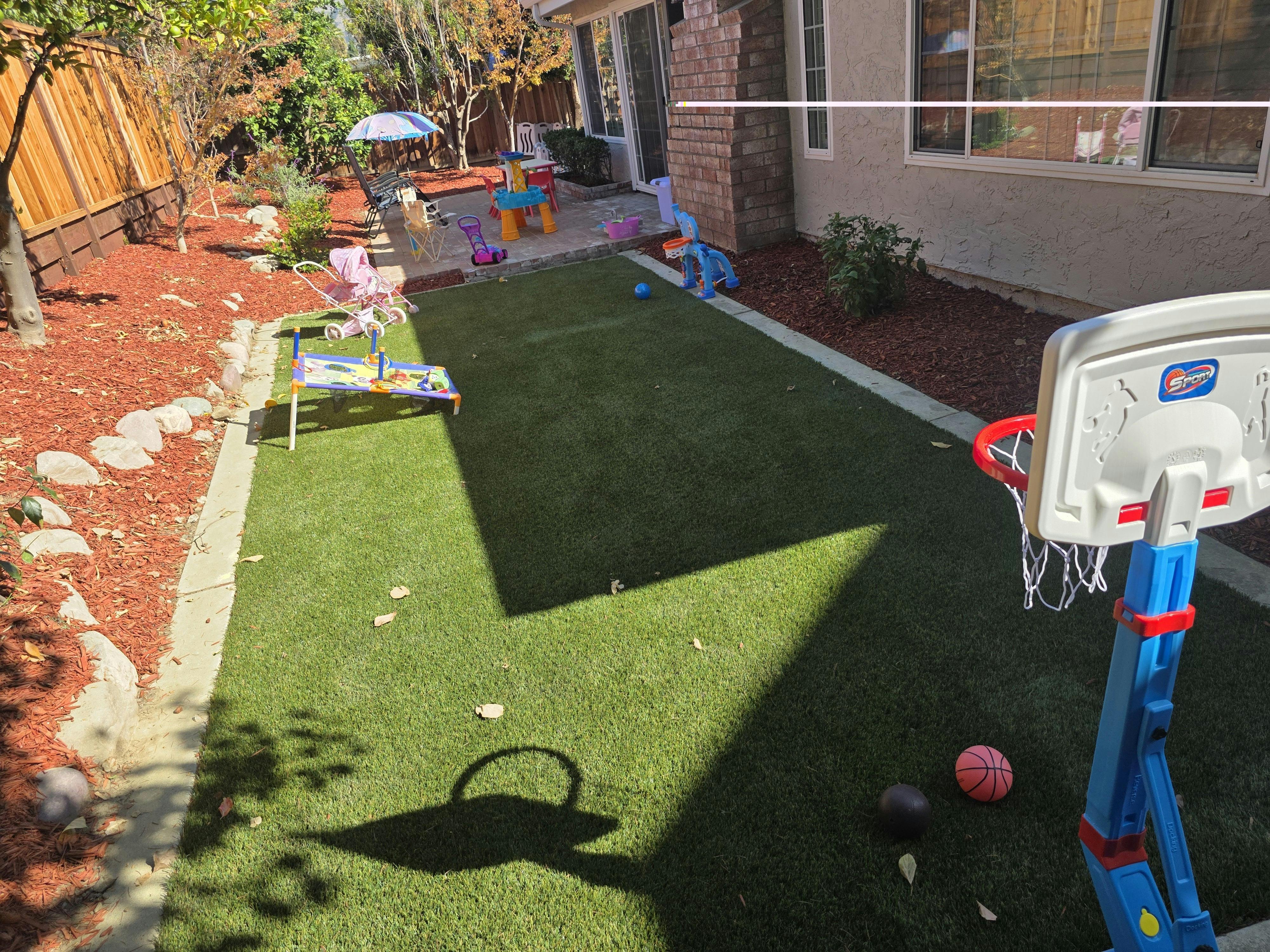 Backyard with artificial turf, a basketball hoop, and children's toys