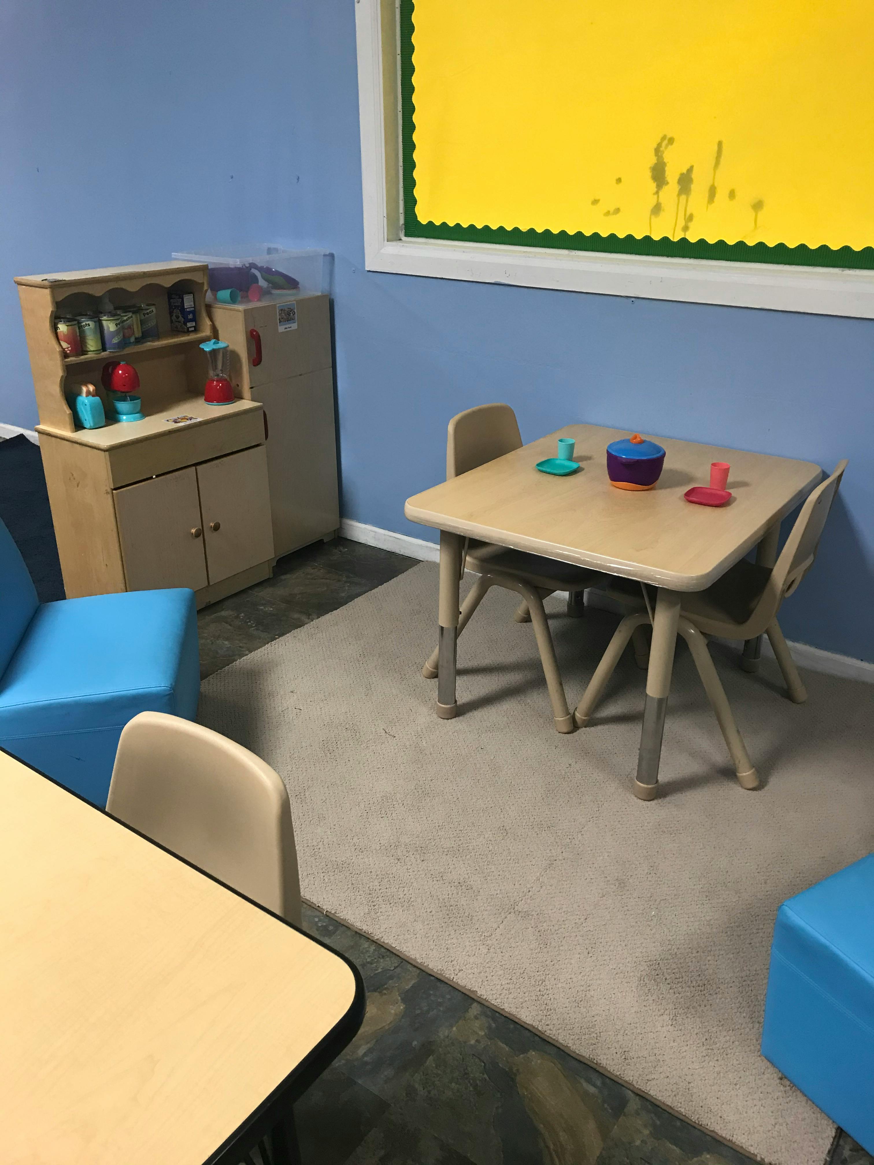Children's play area with small tables and chairs, and a toy kitchen set
