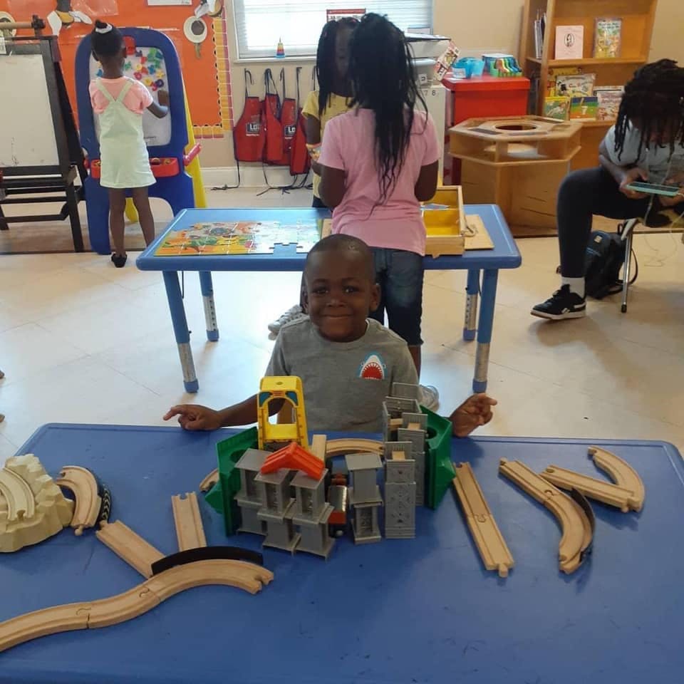 Child playing with a toy train set on a blue table