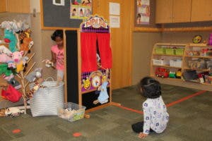 Two children playing with a puppet theater